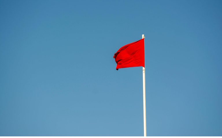 Red flag against clear blue sky-Background Checks